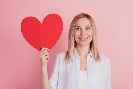 Photo of young attractive woman hhold big paper heart big heart valentine day love romance isolated over pink backgroundの写真素材