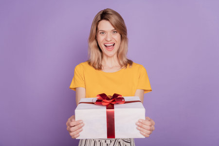 Photo of amazed crazy woman hold big white gift box isolated on violet backgroundの写真素材