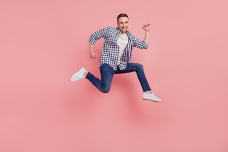 Full size profile side photo of young guy happy positive smile jump go run hurry isolated on pink...