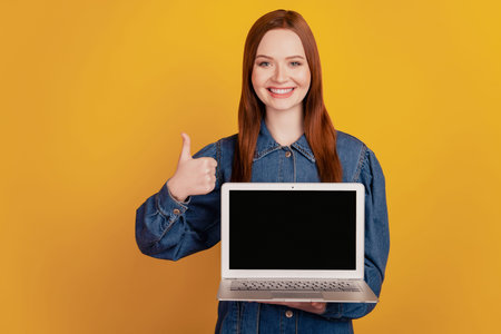 Portrait of lady hold laptop touch screen empty space raise thumb up on yellow background
