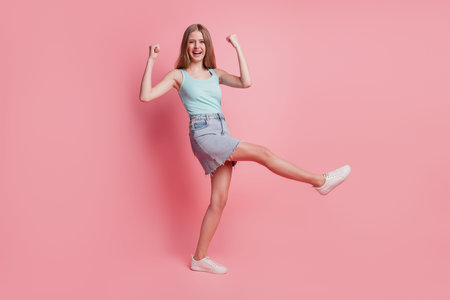 Portrait of cheerful astonished amazed lady raise fists celebrate victory on pink backgroundの写真素材