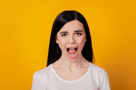 Young girl wearing casual clothes shouting and screaming loud isolated over yellow color backgroundの写真素材
