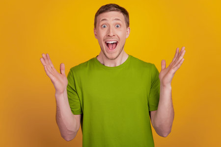 Excited and happy young adult man smiling wide rejoice lucky success standing isolated on yellow...