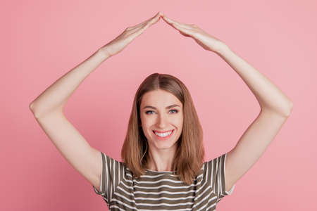Portrait of positive cheerful lady agent hands make roof gesture on pink backgroundの写真素材