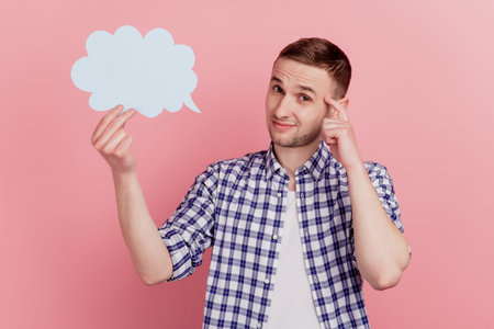 Photo of young man think deeep creative doubt hold paper cloud speech dialog isolated over pastel...