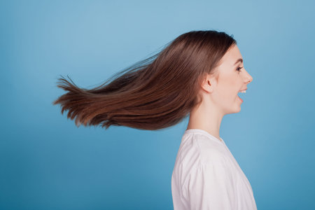 Portrait of crazy excited funky lovely lady look empty space wind blow hairstyle on blue background