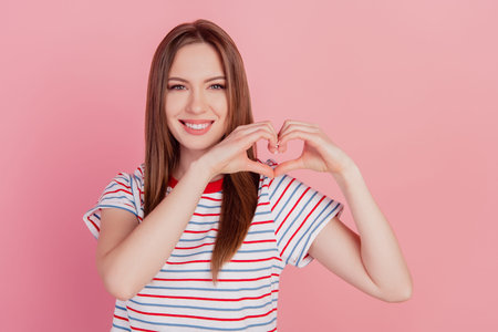 Portrait of charming pretty cute lady fingers show heart sign toothy beaming smile on pink backgroundの写真素材