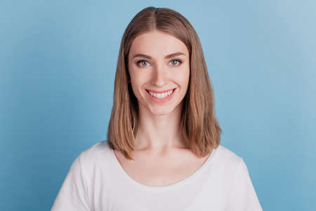 Portrait of cheerful positive adorable girl look camera shiny smile on blue backgroundの写真素材