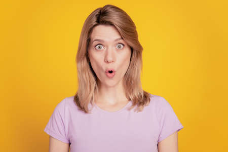 Portrait of shocked funny lady look camera open mouth omg reaction on yellow backgroundの写真素材