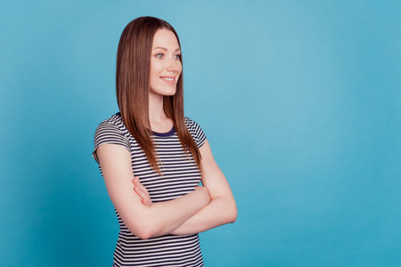 Profile portrait of businesswoman lady shiny smile folded arms look side on blue backgroundの写真素材