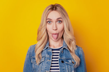 Portrait of funky crazy girl protrude tongue look camera have fun on yellow background