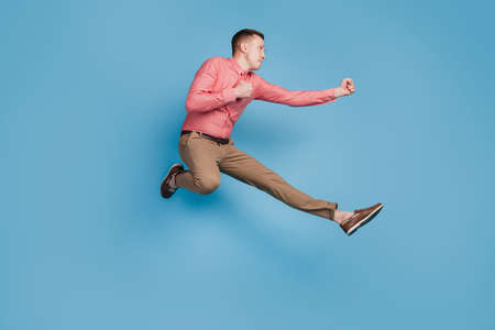 Profile portrait of sporty athletic guy jump hit fists on blue backgroundの写真素材