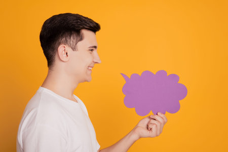 Profile portrait of handsome guy hold paper bubble look empty space on yellow background