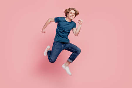 Portrait of funny sportive active guy jump hurry fast run enjoy weekend on pink backgroundの写真素材