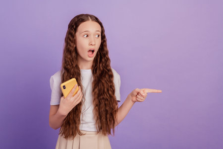 Portrait of crazy promoter reliable girl hold phone direct finger blank space open mouth on violet...