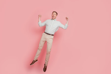Full size photo of rejoicing excited ecstatic man happy positive smile jump up fists hands isolated...