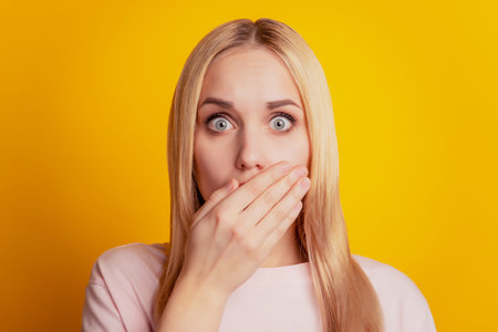 Portrait of crazy omg reaction girl palm cover mouth on yellow backgroundの写真素材