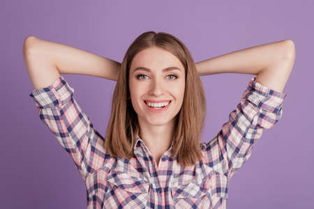 Close up portrait of charming calm pretty cheerful girl holding hands behind head isolated on violet backgroundの写真素材