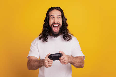 Portrait of excited player guy hold controller amazed reaction open mouth on yellow backgroundの写真素材