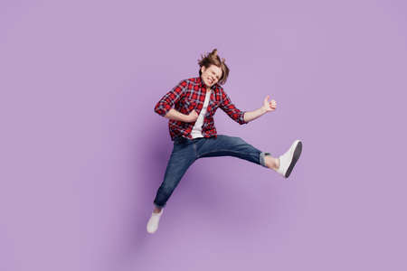 Portrait of entertainer careless cheerful guy jump play imaginary instrument on purple backgroundの写真素材