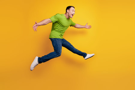 Portrait of sportive energetic guy jump hurry run on yellow wall