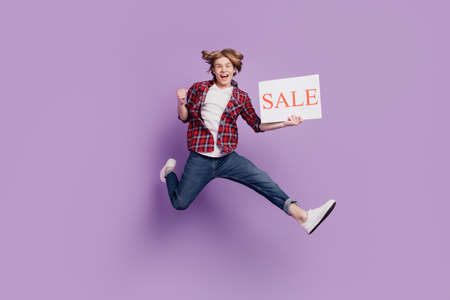 Portrait of joyful athletic promoter guy jump hold sale poster celebrate victory on violet backgroundの写真素材