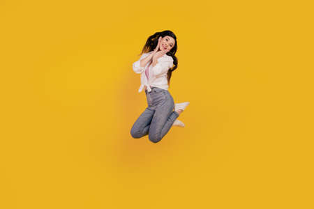 Portrait of adorable positive girl jump posing on yellow backgroundの写真素材