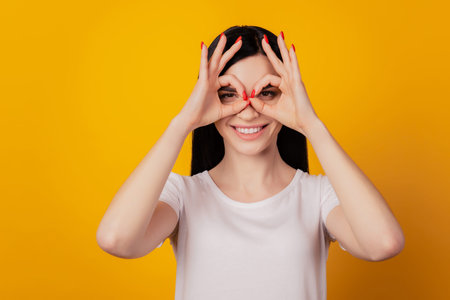 Close-up portrait of attractive amazed girl showing double ok-sign like glasses isolated over bright...