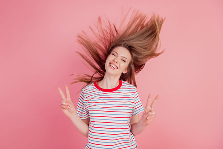 Portrait of cheerful friendly lady show v-signs peace gesture on pink background