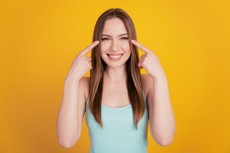 Portrait of promoter adviser reliable lady indicate forefingers healthy eyes on yellow background
