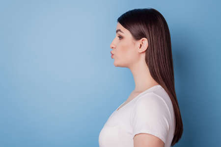 Profile portrait of romantic cute lady look empty space send air kiss on blue backgroundの写真素材