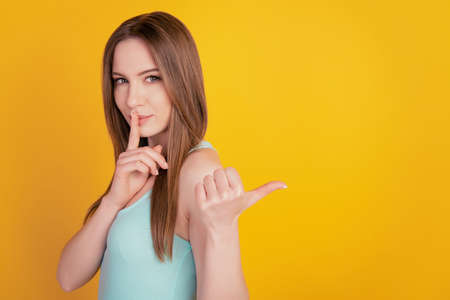 Portrait of tender tempting lady direct thumb blank space finger cover lips ask keep secret on yellow backgroundの写真素材