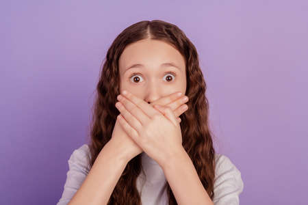 Portrait of terrified anxious little lady crossed hands cover mouth scared look camera on purple backgroundの写真素材