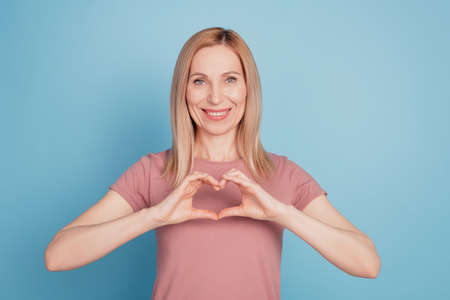 Photo of lady arm fingers making heart figure romantic valentine day wear casual t-shirt isolated blue backgroundの写真素材