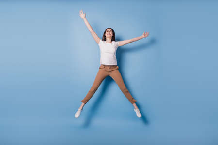 Portrait of dreamy inspired crazy lady jump enjoy weekend time raise hands on blue backgroundの写真素材