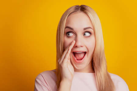 Portrait of excited crazy announcer girl talk look side empty space on yellow backgroundの写真素材