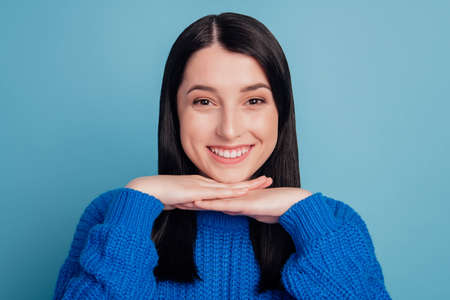 Close-up portrait of yonug woman casual portrait happy positive smile hand touch chin isolated over blue color backgroundの写真素材