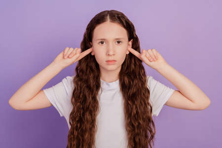 Portrait of kid girl close ears fingers isolated on purple backgroundの写真素材