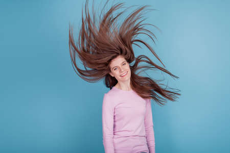 Photo of youg beautiful girl wind blowing hair healthy condition lotion isolated blue color backgroundの写真素材