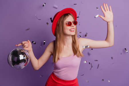 Portrait of lovely pretty lady hold glowing ball dance disco wear hat sunglass pink top on purple backgroundの写真素材