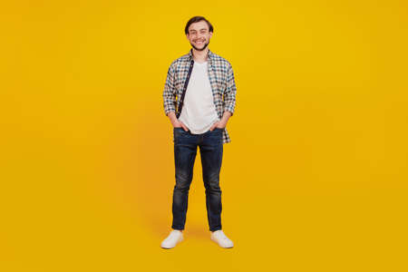 Full length photo of young handsome man happy positive smile confident hands in pocket isolated over yellow color backgroundの写真素材