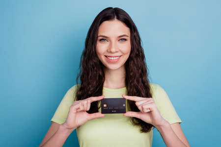 Photo of cheerful promoter girl hold debit card presenting new banking service on blue backgroundの写真素材