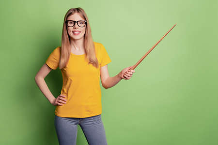 Portrait of positive teacher lady toothy beaming smile hold pointer direct empty space wear spectacles yellow t-shirtの写真素材