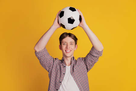 Photo of young man happy positive smile have fun play football game isolated over yellow color backgroundの写真素材