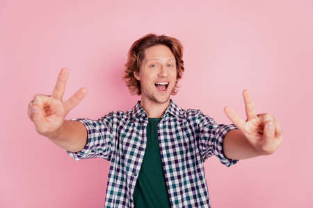 Photo of young cheerful happy excited amazed crazy man showing v-sign isolated on pink color backgroundの写真素材