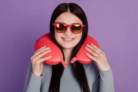 Photo of young cheerful girl eyewear neck pillow trip holiday flight isolated over purple color backgroundの写真素材