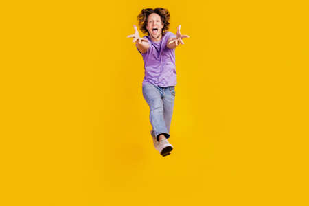 Photo of crazy excited carefree funny man jump open mouth wear casual jeans clothes on yellow backgroundの写真素材