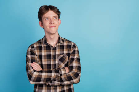 Photo of young attractive man happy dream curious look empty space crossed hands isolated over blue color backgroundの写真素材
