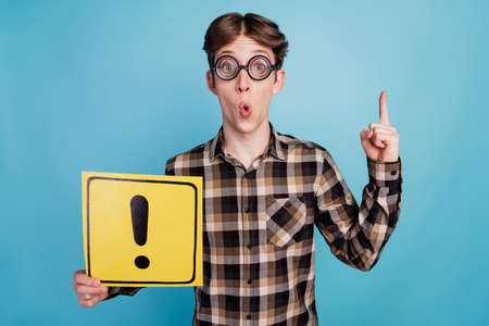 Photo of young man hold paper card sign exclamation mark point finger idea choice isolated over blue color backgroundの写真素材