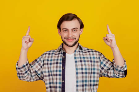 Photo of young attractive man happy smile point fingers empty space promo advert choice isolated over yellow color backgroundの写真素材